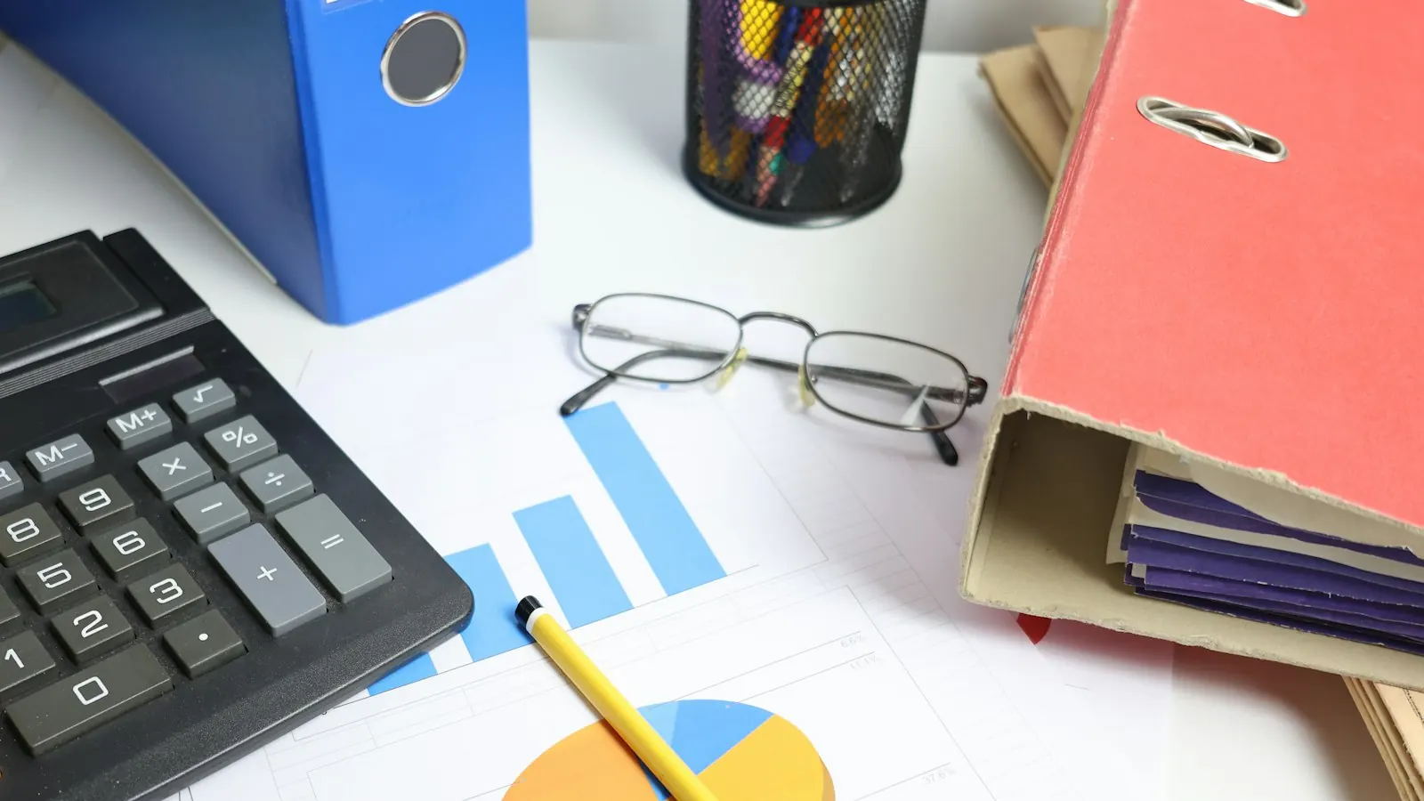 Desk with a calculator, charts and binders